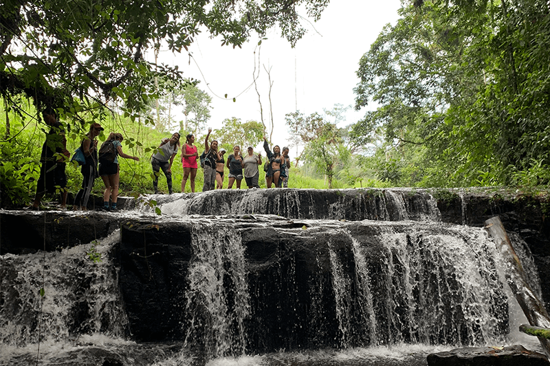 Grupo de caminantes cruzando terreno variado y natural
